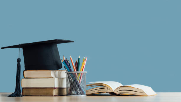 graduation day.a mortarboard and graduation scroll on stack of books with pencils color in a pencil case on blue background.education learning concept. - 教育 個照片及圖片檔